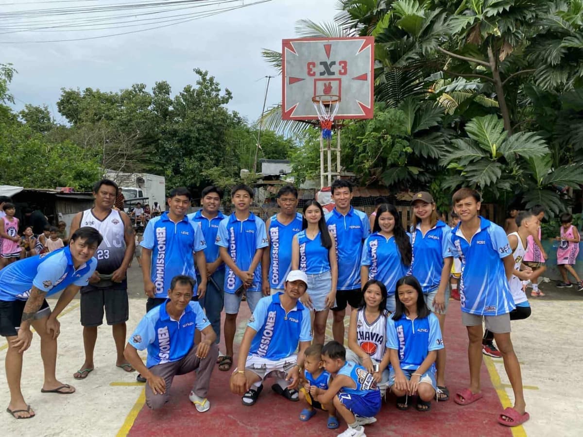 Gloria barangay team and supporters in light blue jerseys beside a street court